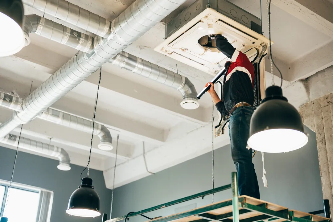 Technician servicing a ceiling cassette air conditioner